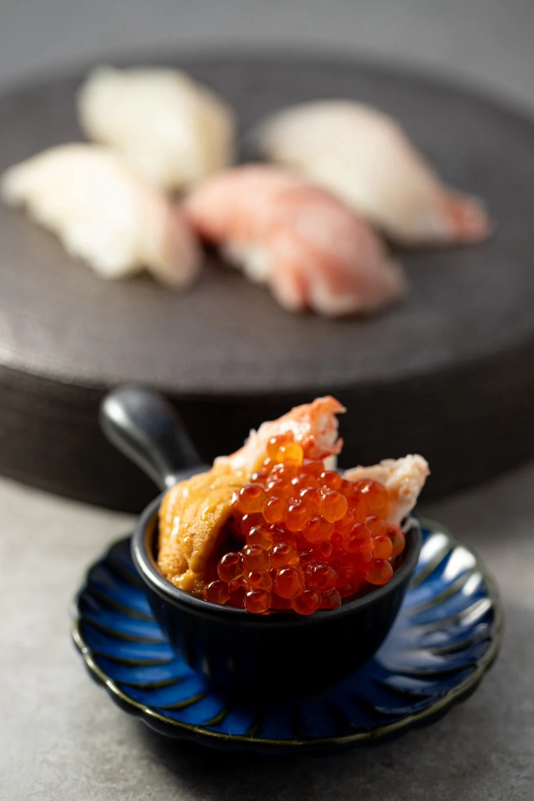 雲丹・いくら・蟹を盛った結びの小丼と、奥に並ぶ握り